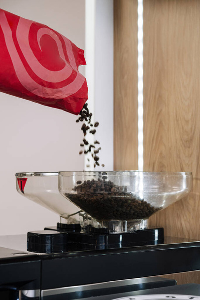 Fresh coffee beans flowing into a coffee grinder, ready for brewing - Photo, Image