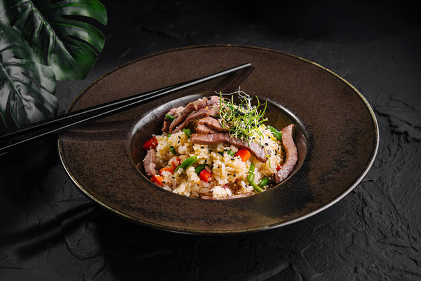 Вишукана миска з яловичого смаженого рису з овочами, прикрашена мікрогрінками, подається з паличками - Фото, зображення