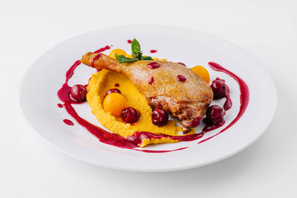 Elegant presentation of duck confit on a bed of creamy puree with vibrant berry sauce - Photo, Image