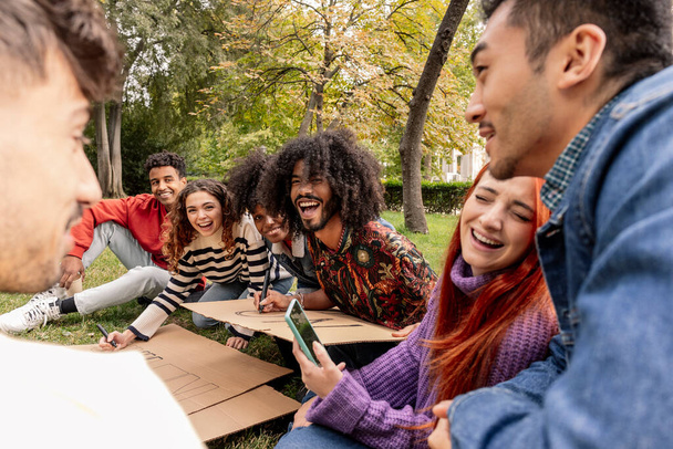 Grupa żywych przyjaciół gromadzi się w parku, śmiejąc się i tworząc znak, który promuje pokój i jedność. - Zdjęcie, obraz