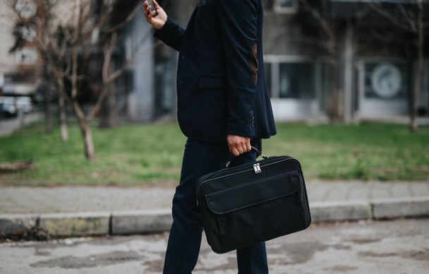 Fiducioso maschio passi professionali su un marciapiede della città, tenendo una valigetta elegante sulla sua strada per lavorare. - Foto, immagini