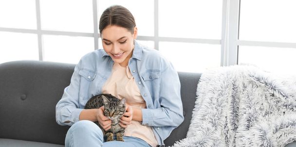 Schöne junge Frau mit süßer Katze sitzt auf Sofa - Foto, Bild