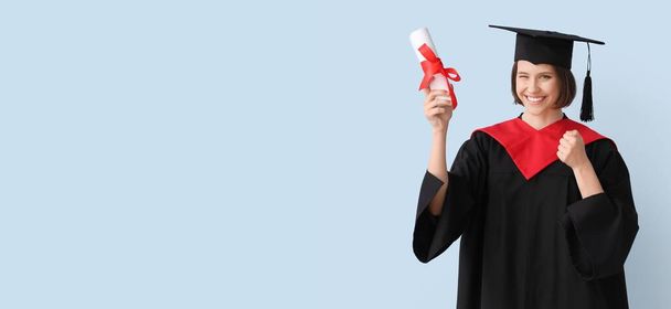 Happy female graduating student držící diplom na světle modrém pozadí s prostorem pro text - Fotografie, Obrázek