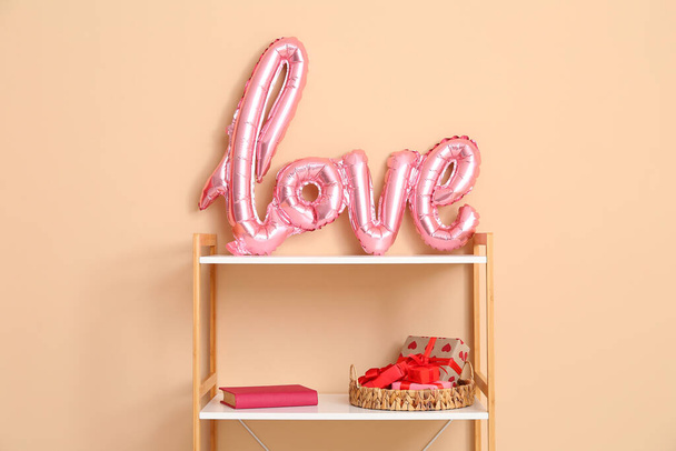 Libreria con scritta LOVE realizzata con palloncini e scatole regalo vicino alla parete beige. Festa di San Valentino - Foto, immagini