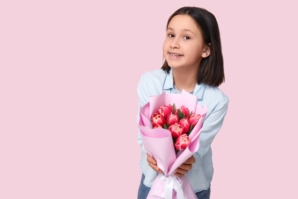 Kleines Mädchen mit Tulpenstrauß in der Nähe der rosa Wand - Foto, Bild
