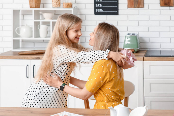 Menina bonito com caixa de presente para o Dia das Mães abraçando sua mãe em casa - Foto, Imagem
