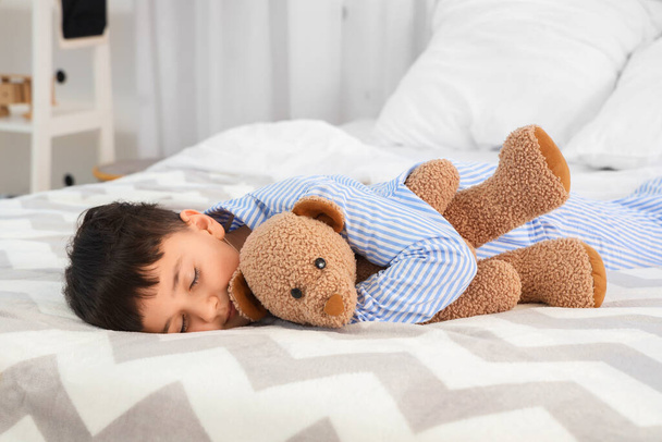 Милий маленький хлопчик з плюшевим ведмедем спить у спальні - Фото, зображення