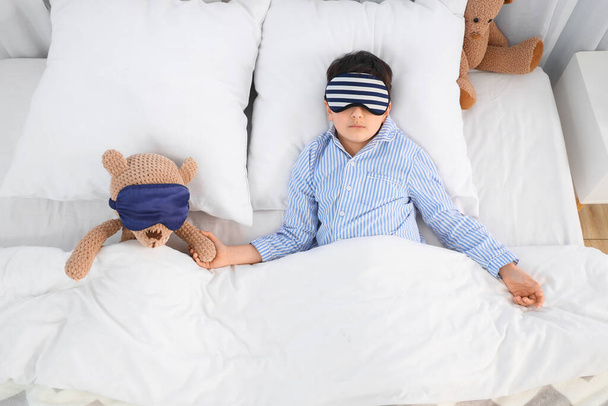 Lindo niño con osito de peluche y máscaras para dormir en el dormitorio - Foto, Imagen