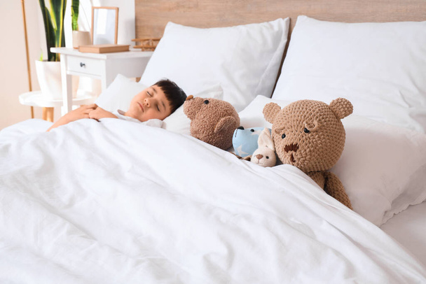 Schattig jongetje met speelgoed slapen in slaapkamer - Foto, afbeelding