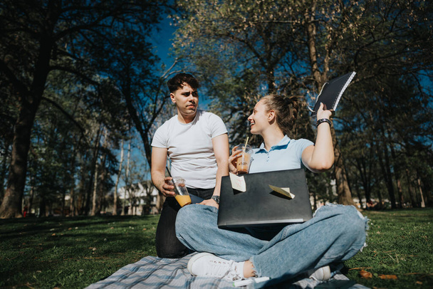 Nastoletni licealiści uczą się razem na świeżym powietrzu, współpracują przy projekcie na trawniku kampusu w słoneczny dzień. - Zdjęcie, obraz