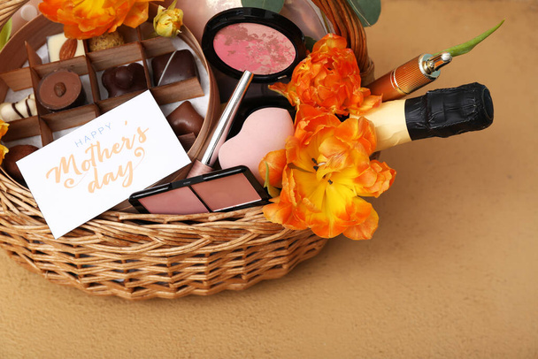 Geschenkkorb mit Bonbons, Kosmetik und Tulpenblumen zum Muttertag auf Farbtisch, Nahaufnahme - Foto, Bild