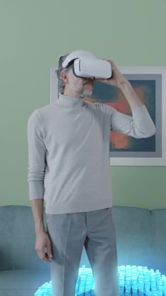 Powiększ widok dojrzałego mężczyzny zakładającego okulary VR i zaczynającego przeglądać strony internetowe w cyberprzestrzeni w domu. Strzał pionowy - Materiał filmowy, wideo