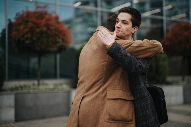 Un joven hombre de negocios en un traje está extendiendo los brazos fuera de un edificio moderno, tomando un descanso relajante. - Foto, imagen