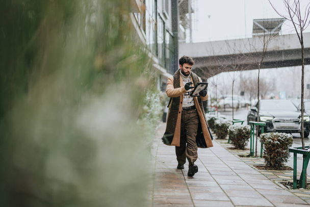 Professzionális üzletember digitális táblagépet használ havas járdán, kapcsolatban marad és dolgozik, miközben a szabadban sétál. - Fotó, kép