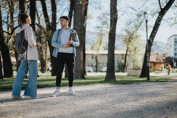 Zwei junge Studenten oder Freunde unterhalten sich im Freien mit Büchern in der Hand und halten einen Moment des akademischen Lebens fest. - Foto, Bild