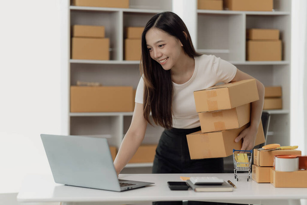 Починаючи бізнес, Азіатська жінка працює підприємцем МСП, новий бізнес з коробкою для упаковки ноутбуків, приймає замовлення, ім'я, готується відправити клієнту. - Фото, зображення