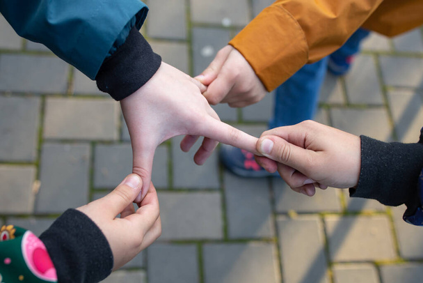 Vier Kinderhände ziehen an Fingern, Kinder spielen im Park - Foto, Bild