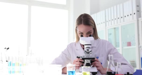 Laboratuvarlarda birlikte çalışan iki bilimadamı mikroskop inceliyor. Kimyasal Tıbbi İlaç Laboratuvarında ekip çalışması - Video, Çekim