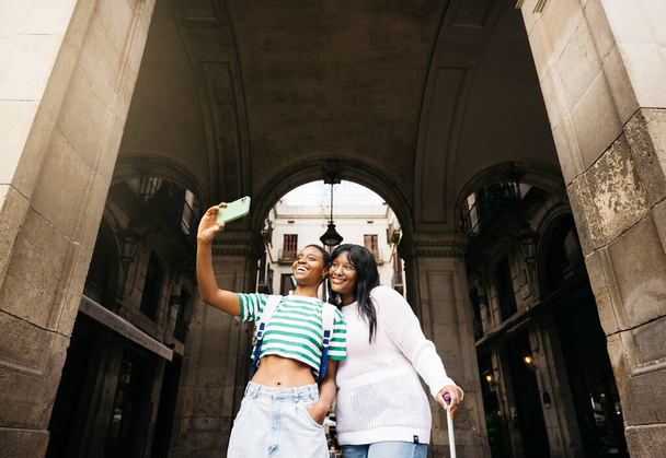 Mladé lesbičky pár brát selfie ve starém městě evropského města během cestování.Mladé lesbičky pár objevovat staré město velkého města během krátkého víkendu výlet. - Fotografie, Obrázek