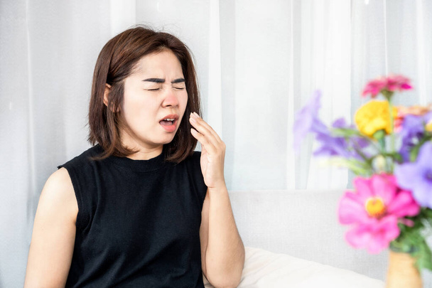 allergica donna asiatica soffre di sintomi di allergia al polline starnuti e ha naso che cola con fiore in fiore in soggiorno  - Foto, immagini