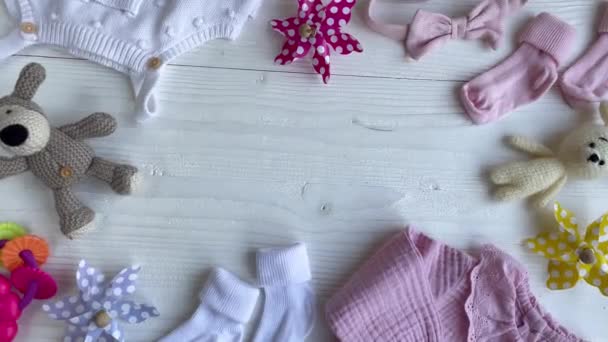 Conjunto de macacões de bebê, calças, meias e brinquedo de malha. Moda roupas de bebê e acessórios. Deitado plano, vista superior - Filmagem, Vídeo