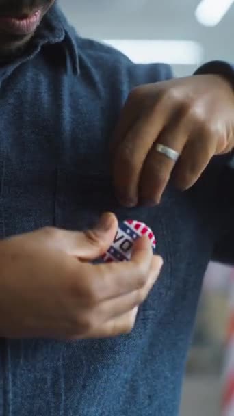 Um eleitor ou empresário afro-americano anônimo coloca um crachá com o logotipo e a inscrição da bandeira dos EUA I Voted. Cidadão dos EUA no posto de voto durante as eleições. Dia Nacional das Eleições nos Estados Unidos. - Filmagem, Vídeo