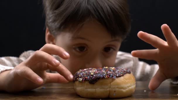 Késleltetett kielégülés - Fiatal fiú akar enni fánk az asztalon, széles nyitott bámult édes desszert snack, hogy türelmes - Felvétel, videó