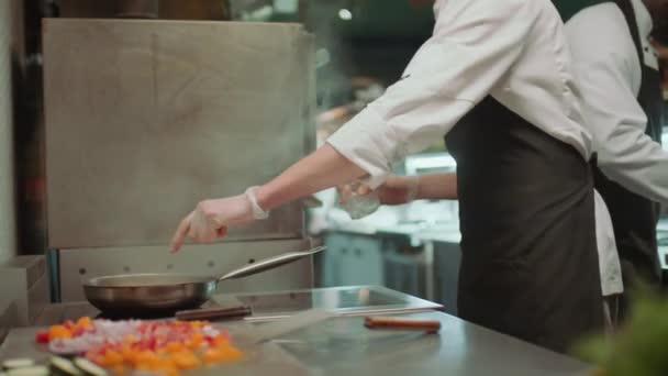 Professioneller Koch, der Alkohol in die Pfanne gießt, Feuer entzündet und Essen dreht, während er in der Restaurantküche Flamme kocht - Filmmaterial, Video