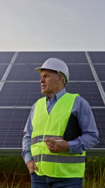 Dělník nebo inženýr stojí před solárními panely a dívá se do kamery. 4K video UHD - Záběry, video