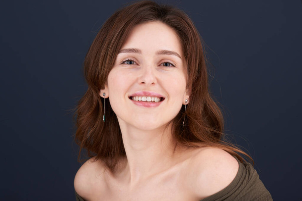 Μια όμορφη νεαρή γυναίκα με καστανά μαλλιά και πράσινα μάτια χαμογελώντας απευθείας στην κάμερα - Φωτογραφία, εικόνα
