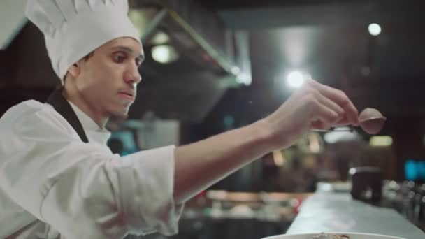 Chef sieben Gewürze über gekochten Fleischsteaks, während er in der Restaurantküche Essen auf dem Teller serviert - Filmmaterial, Video