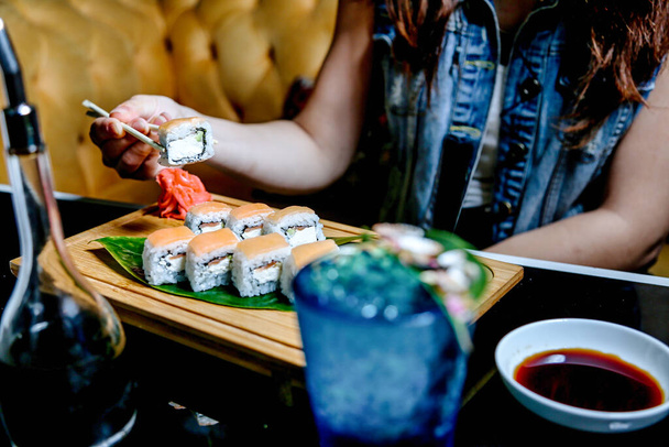 Una donna è seduta a un tavolo con un piatto di sushi, godendo tranquillamente il suo pasto. - Foto, immagini