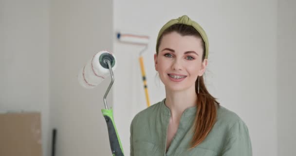 Do-it-yourself interior decorating. Joy and satisfaction in her self-directed home renovation project. A young woman is captured smiling as she embarks on painting the walls of her new apartment - Footage, Video