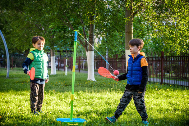 Kaksi ystävää pelaa liekapallo swing pallo peli kesällä camping. Kaksi poika veli onnellinen vapaa terve aktiivinen aika ulkona käsite. - Valokuva, kuva