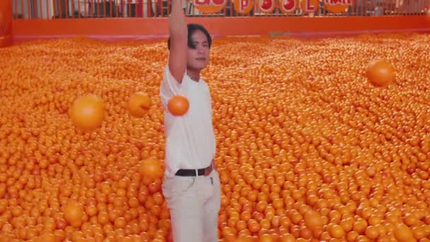 Mann läuft bei Tageslicht durch eine Lagerhalle voller Orangen, Konzept der industriellen Landwirtschaft - Filmmaterial, Video