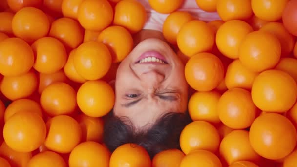 Criança cercada por bolas laranja brilhantes, conceito lúdico e colorido durante o dia - Filmagem, Vídeo