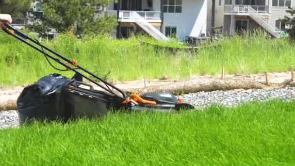 W domu mieszkalnym na przedmieściach bujny zielony trawnik jest skrupulatnie koszony za pomocą kosiarki elektrycznej, tworząc dobrze wypielęgnowaną i zapraszającą przestrzeń na zewnątrz. - Materiał filmowy, wideo