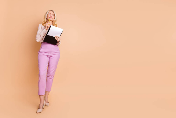 Full body photo of retired female hold paperholder documents look empty space wear trendy formalwear isolated on beige color background. - Fotó, kép