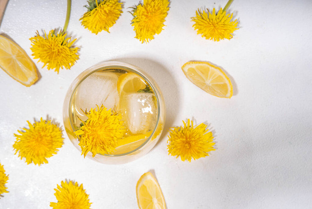 タンポポポ 冷たいアイスティーまたはレモネード. 白いテーブルの背景のコピースペースにタンポの花と根,レモンとシロップを植えるハーブフラワードリンク - 写真・画像