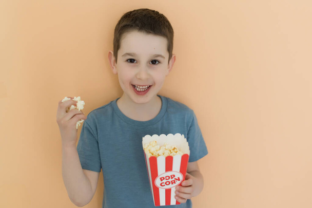 kavkazský chlapec s popcornem na béžovém pozadí, kopírovací prostor - Fotografie, Obrázek
