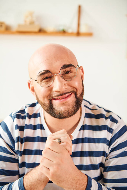 Ein glatzköpfiger Mann mit Brille posiert nachdenklich zu Hause. - Foto, Bild