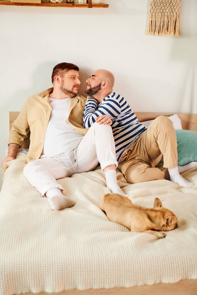 Kaksi miestä makaa sängyllä ranskanbulldoggi vierellään.. - Valokuva, kuva