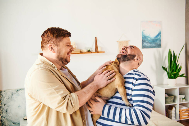 Un hombre con amor sostiene un Bulldog francés en un acogedor ambiente de sala de estar. - Foto, Imagen