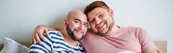 Un couple gay assis ensemble sur un lit. - Photo, image