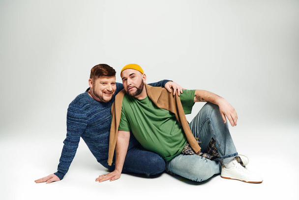 Zwei Männer sitzen auf dem Boden und posieren für ein Foto. - Foto, Bild