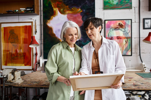 Two mature women stand, collaborating in an art studio filled with inspiration. - Foto, Imagem