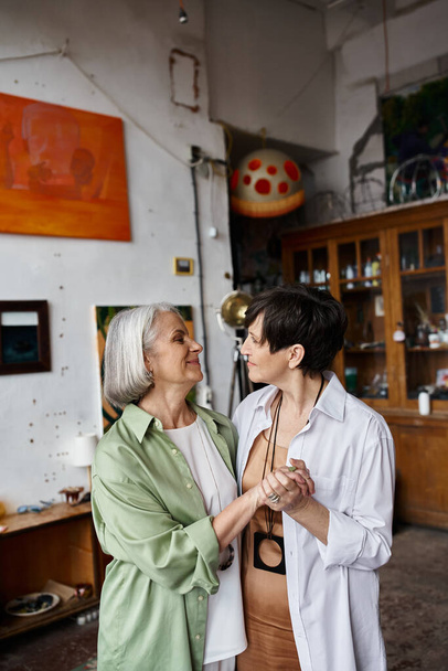 Two mature women stand together in an art studio. - Zdjęcie, obraz