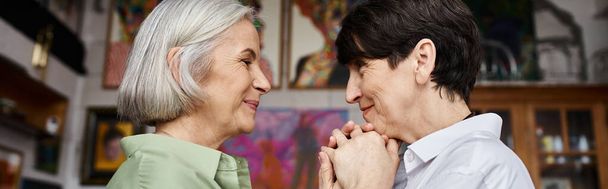 Mature lesbian couple stands together in art studio. - Photo, Image