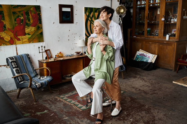 Ένα ώριμο λεσβιακό ζευγάρι σε ένα καλλιτεχνικό στούντιο, να στέκεται μαζί. - Φωτογραφία, εικόνα