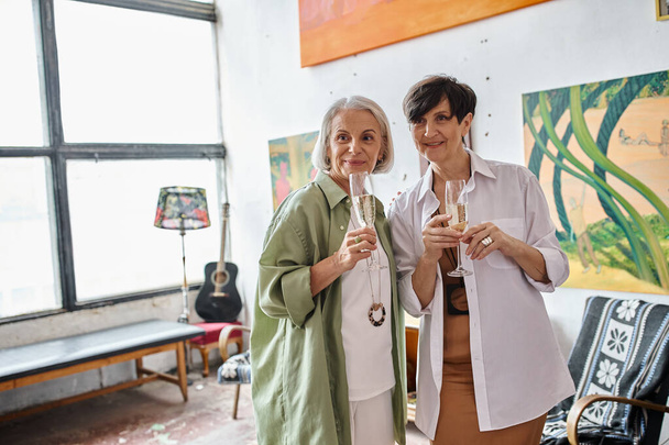 Una coppia lesbica matura in uno studio d'arte, in piedi vicino insieme. - Foto, immagini